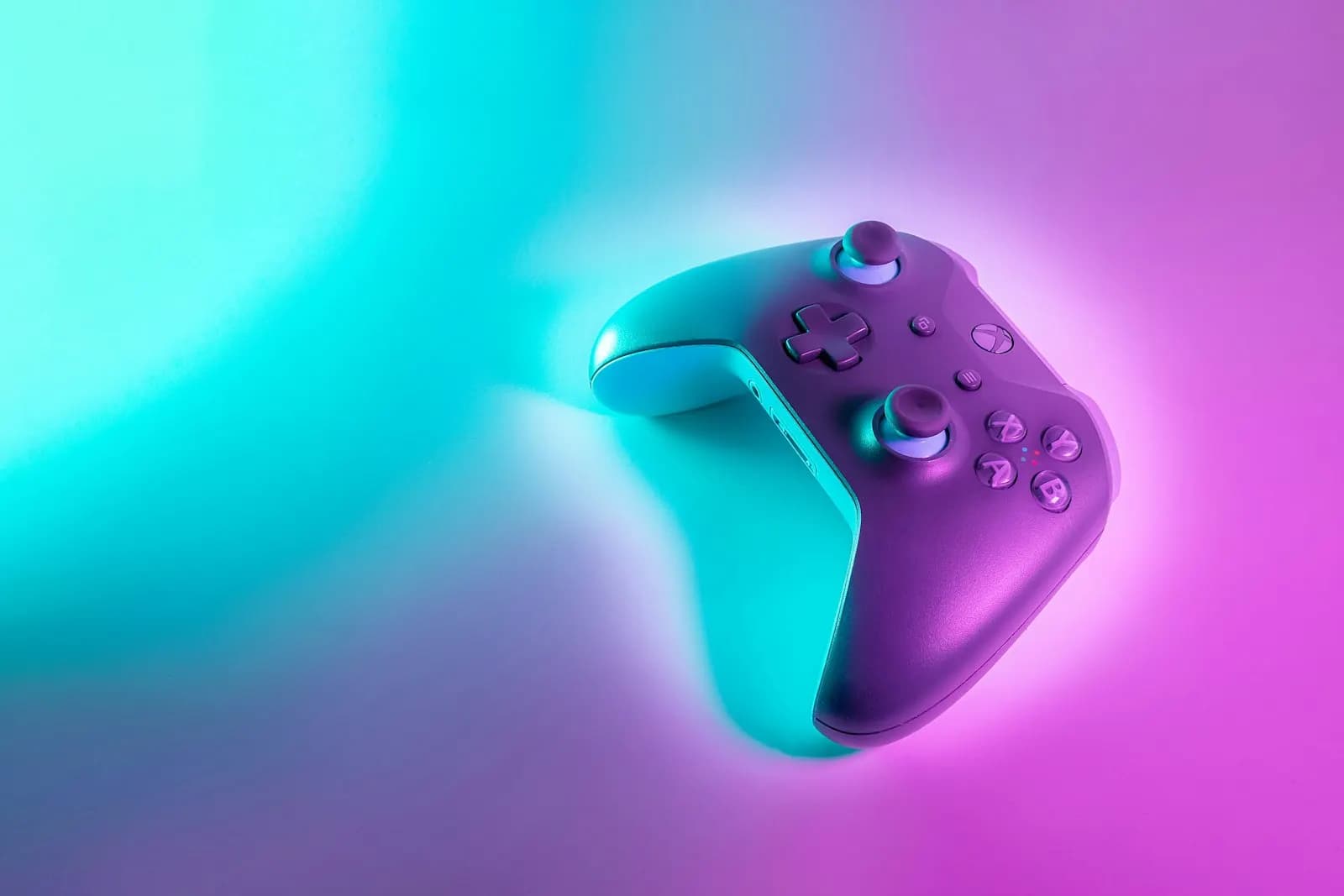 A game controller lit in cyan and violet